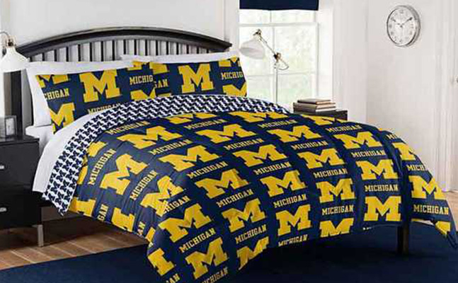 a bed with university of michigan pillows and comforter