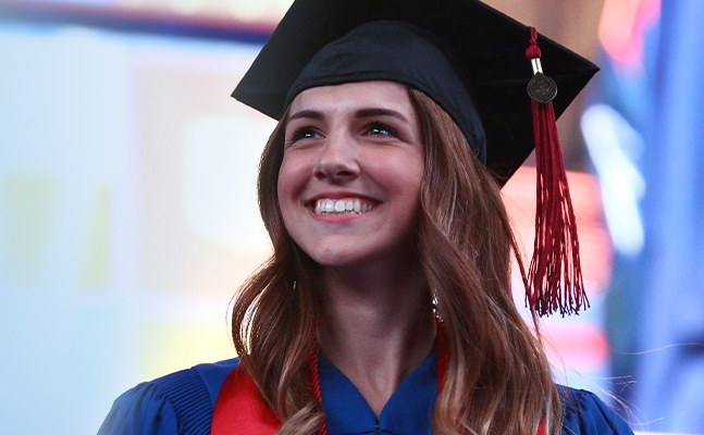 A woman in blue and red graduation robe, smiling